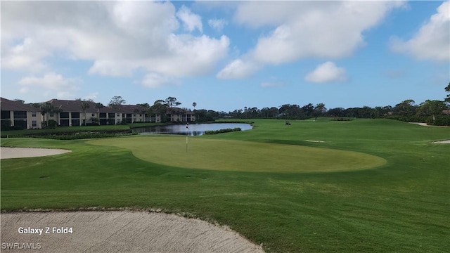 view of home's community featuring view of golf course, a lawn, and a water view