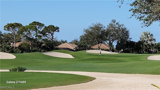 view of community with view of golf course and a yard