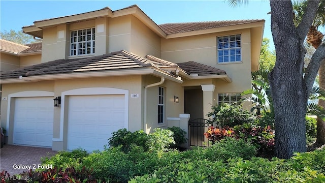 view of front facade with a garage, a tile roof, decorative driveway, and stucco siding