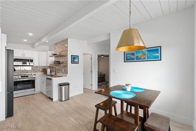 kitchen featuring decorative light fixtures, tasteful backsplash, white cabinetry, light hardwood / wood-style floors, and stainless steel appliances