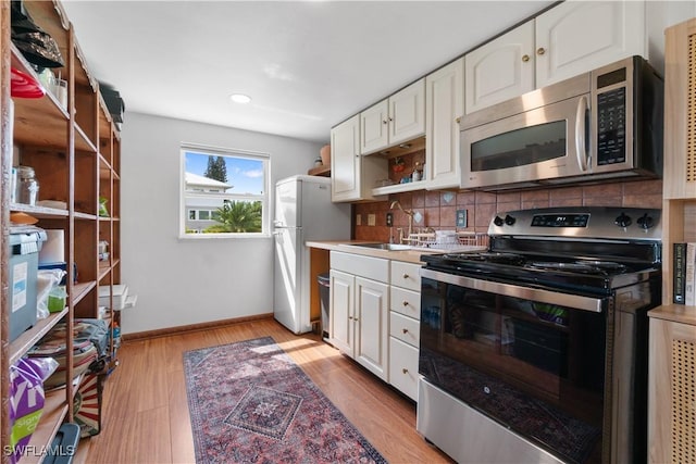 kitchen with sink, white cabinets, backsplash, light hardwood / wood-style floors, and stainless steel appliances