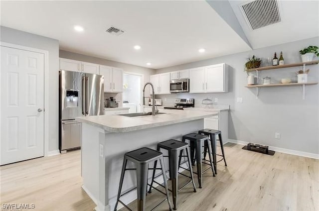 kitchen with stainless steel appliances, white cabinetry, a breakfast bar, and sink