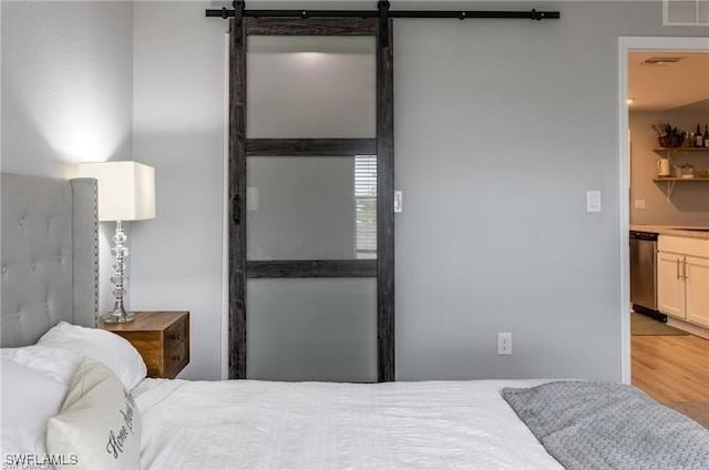 bedroom featuring wood-type flooring and a barn door