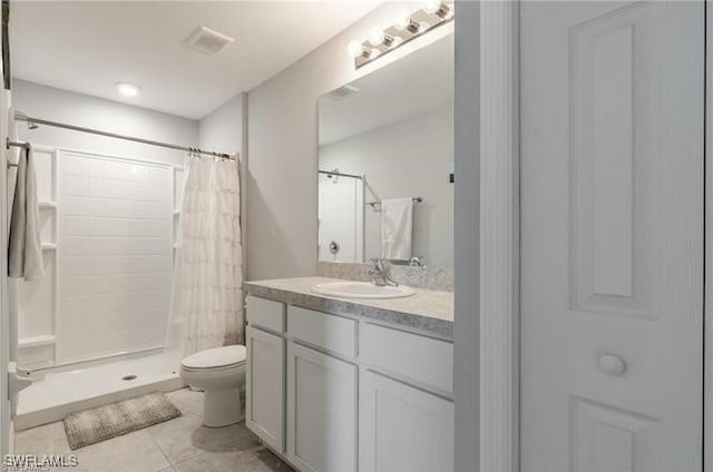 bathroom with tile patterned floors, vanity, toilet, and curtained shower