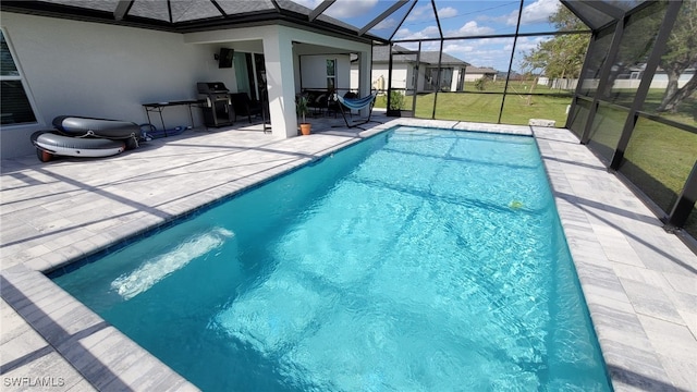 view of swimming pool featuring a yard, a patio area, and glass enclosure