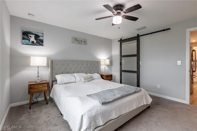 carpeted bedroom featuring a barn door and ceiling fan