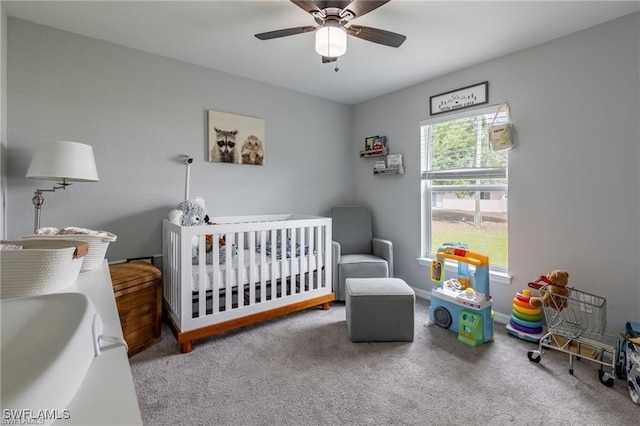 bedroom with a nursery area, carpet flooring, and ceiling fan