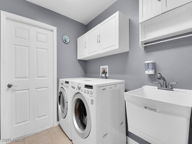 laundry area featuring light tile patterned floors, sink, cabinets, and independent washer and dryer