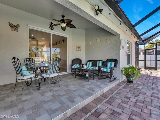 view of patio featuring ceiling fan, outdoor lounge area, and glass enclosure