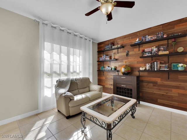 tiled living room with ceiling fan and wooden walls