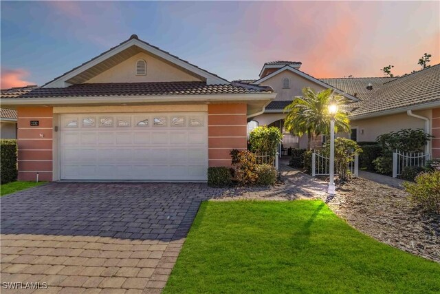 view of front of property with a garage and a lawn