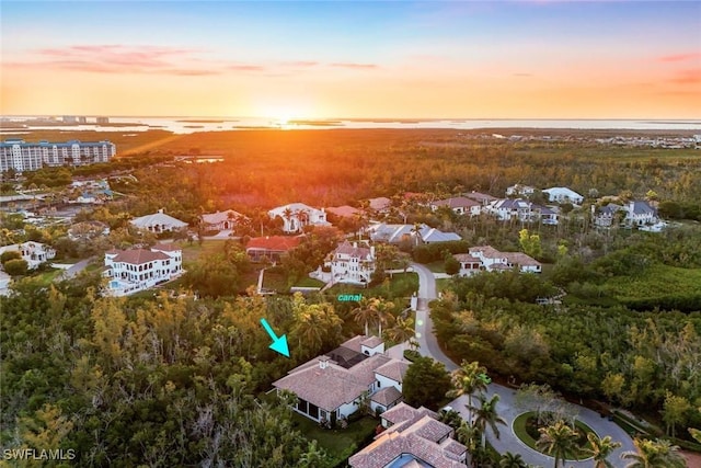 aerial view at dusk featuring a water view