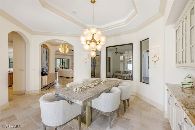 dining area featuring a raised ceiling, ornamental molding, and a notable chandelier