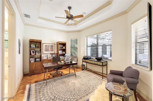 home office with light parquet flooring, ornamental molding, ceiling fan, and a tray ceiling