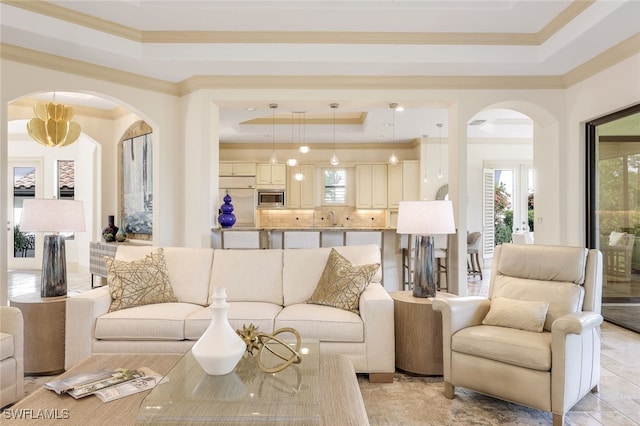 living room with sink, ornamental molding, and a raised ceiling