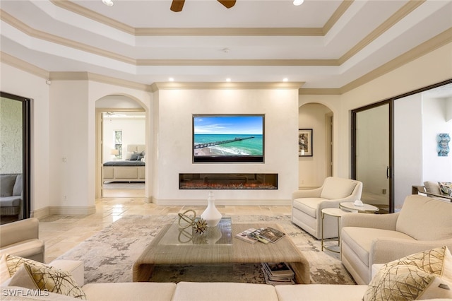 living room with ceiling fan, ornamental molding, and a tray ceiling