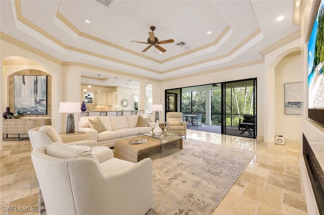 living room featuring ornamental molding, a raised ceiling, and ceiling fan