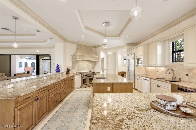 kitchen with premium range hood, a tray ceiling, built in appliances, and pendant lighting