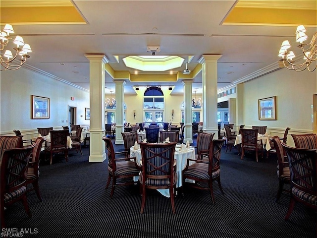 carpeted dining space with a tray ceiling, a notable chandelier, crown molding, and ornate columns