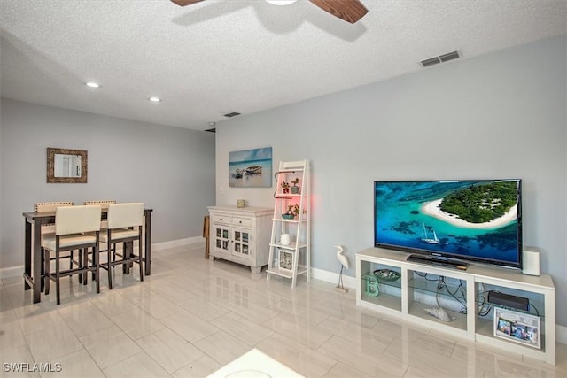 living room featuring ceiling fan and a textured ceiling