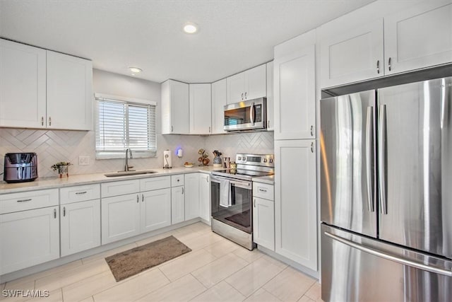 kitchen with stainless steel appliances, sink, and white cabinets