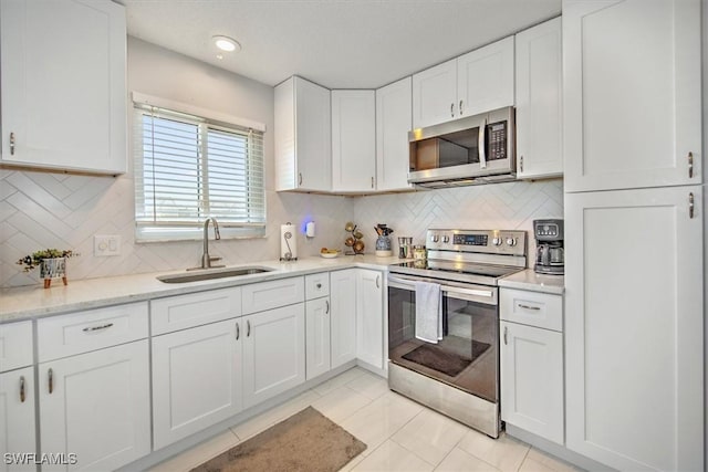 kitchen featuring sink, appliances with stainless steel finishes, tasteful backsplash, light stone countertops, and white cabinets