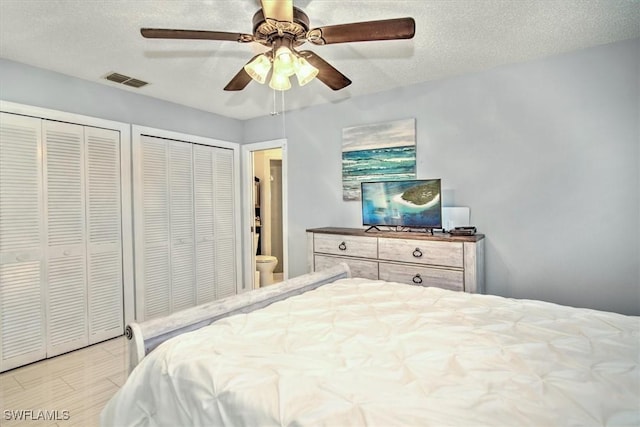 bedroom featuring ceiling fan, two closets, and a textured ceiling