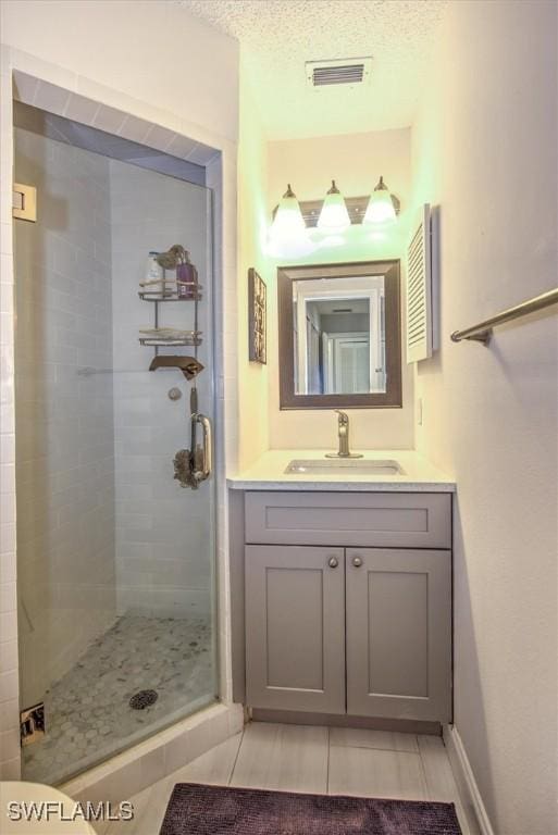 bathroom featuring tile patterned flooring, vanity, an enclosed shower, and a textured ceiling