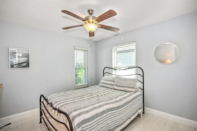 bedroom featuring multiple windows, ceiling fan, and a textured ceiling