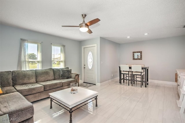 living room with ceiling fan and a textured ceiling