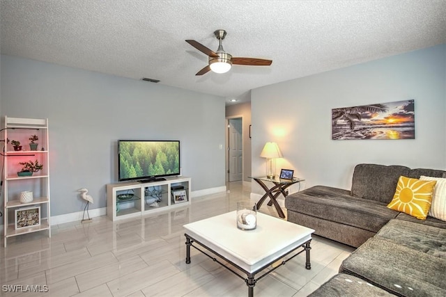 living room with ceiling fan and a textured ceiling