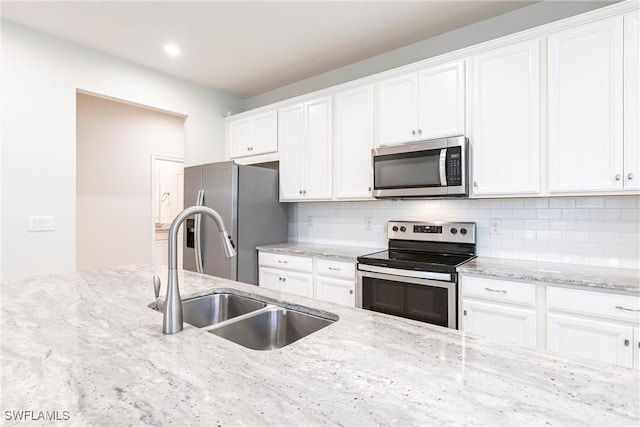 kitchen featuring sink, white cabinetry, tasteful backsplash, light stone counters, and stainless steel appliances