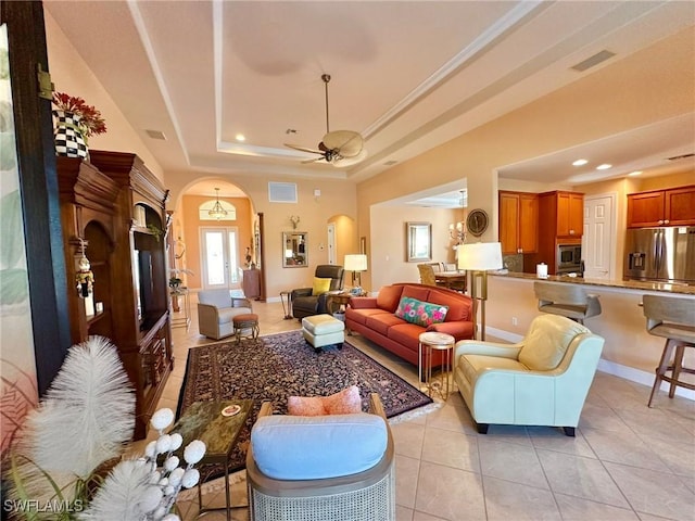 living room with visible vents, arched walkways, light tile patterned floors, a raised ceiling, and ceiling fan