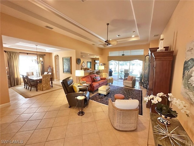 living area with light tile patterned flooring, plenty of natural light, arched walkways, and a raised ceiling