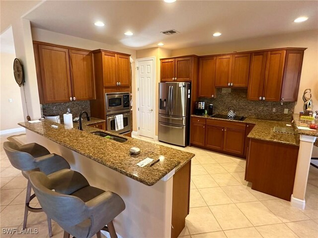 28880 Kiranicola Ct, Bonita Springs, FL 34135 - kitchen with appliances with stainless steel finishes, a peninsula, light tile patterned flooring, dark stone counters, and a kitchen breakfast bar