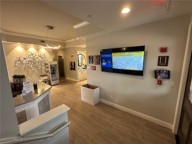 interior space featuring crown molding, wood finished floors, visible vents, and baseboards