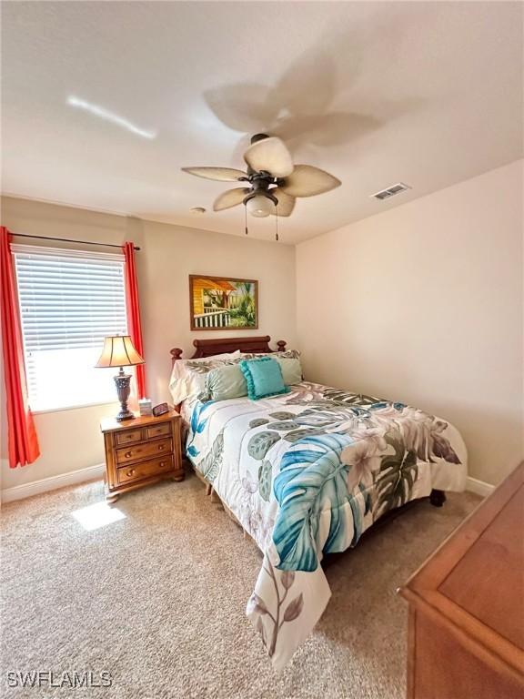 carpeted bedroom with baseboards, visible vents, and ceiling fan