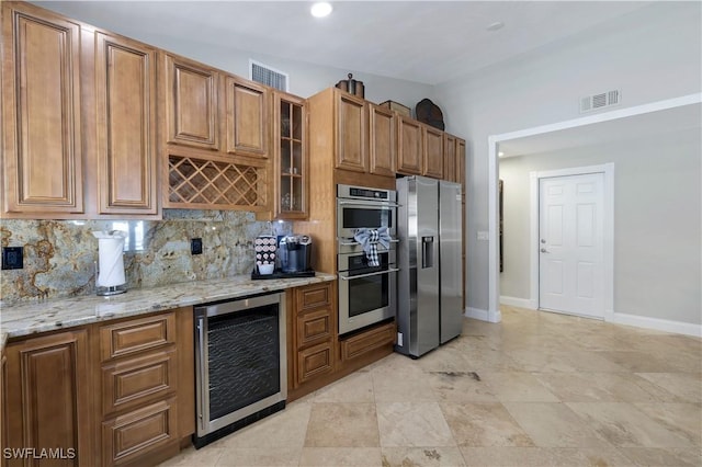 kitchen with wine cooler, lofted ceiling, light stone counters, stainless steel appliances, and backsplash