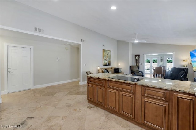 kitchen featuring black electric cooktop, ceiling fan, lofted ceiling, and light stone countertops