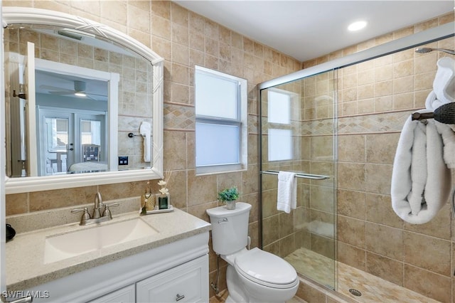 bathroom featuring vanity, a shower with shower door, tile walls, and toilet