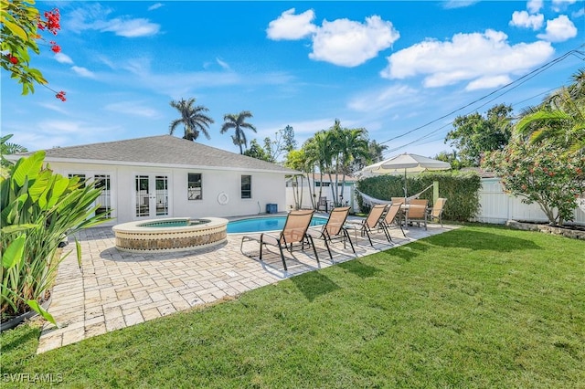 back of property with a swimming pool with hot tub, a patio, a yard, and french doors