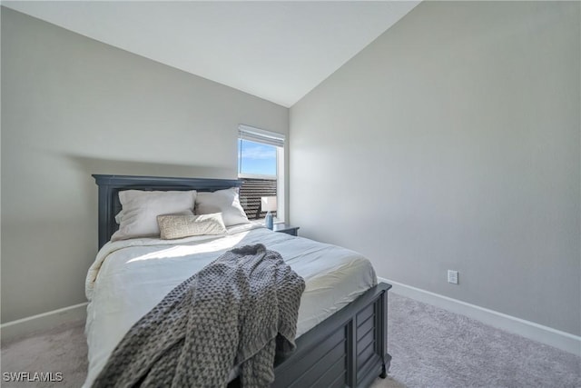 bedroom with light carpet, vaulted ceiling, and baseboards