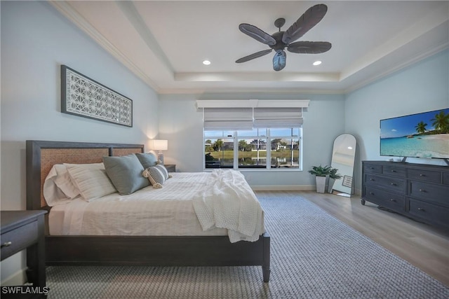 bedroom with light wood finished floors, a tray ceiling, recessed lighting, and crown molding