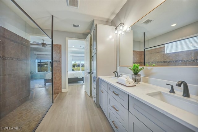 bathroom featuring vanity, hardwood / wood-style floors, tiled shower, and ceiling fan