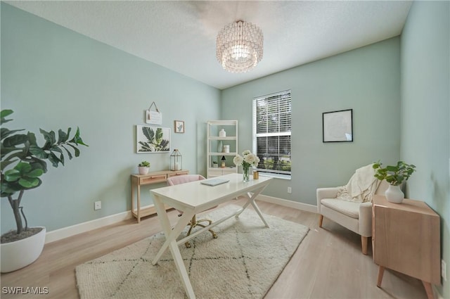 office space with a chandelier, light wood finished floors, and baseboards