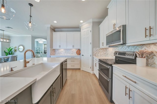 kitchen featuring pendant lighting, stainless steel appliances, light countertops, and white cabinets