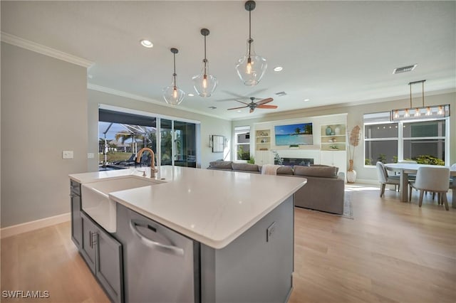 kitchen with sink, crown molding, stainless steel dishwasher, an island with sink, and pendant lighting