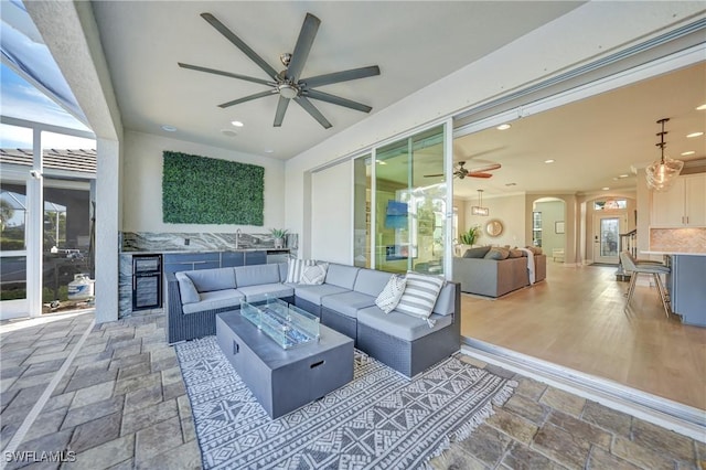 view of patio / terrace with sink, an outdoor living space with a fire pit, beverage cooler, and ceiling fan