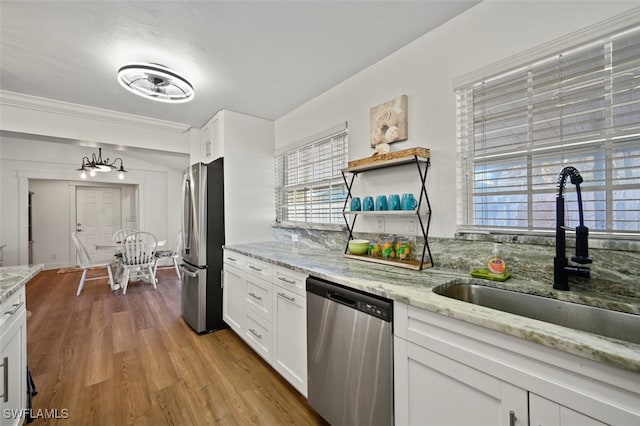 kitchen with sink, light hardwood / wood-style flooring, appliances with stainless steel finishes, light stone countertops, and white cabinets