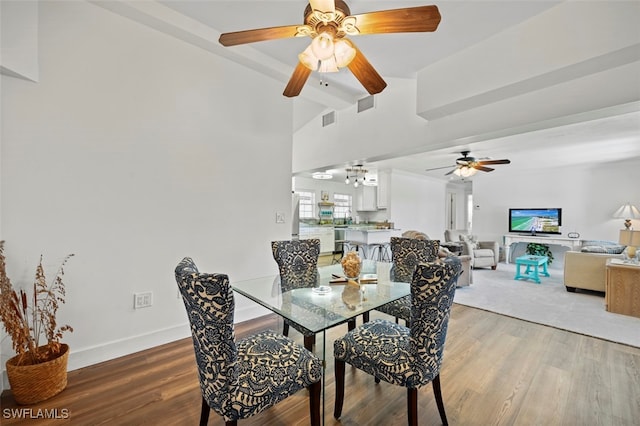 dining room featuring hardwood / wood-style flooring, vaulted ceiling with beams, and ceiling fan